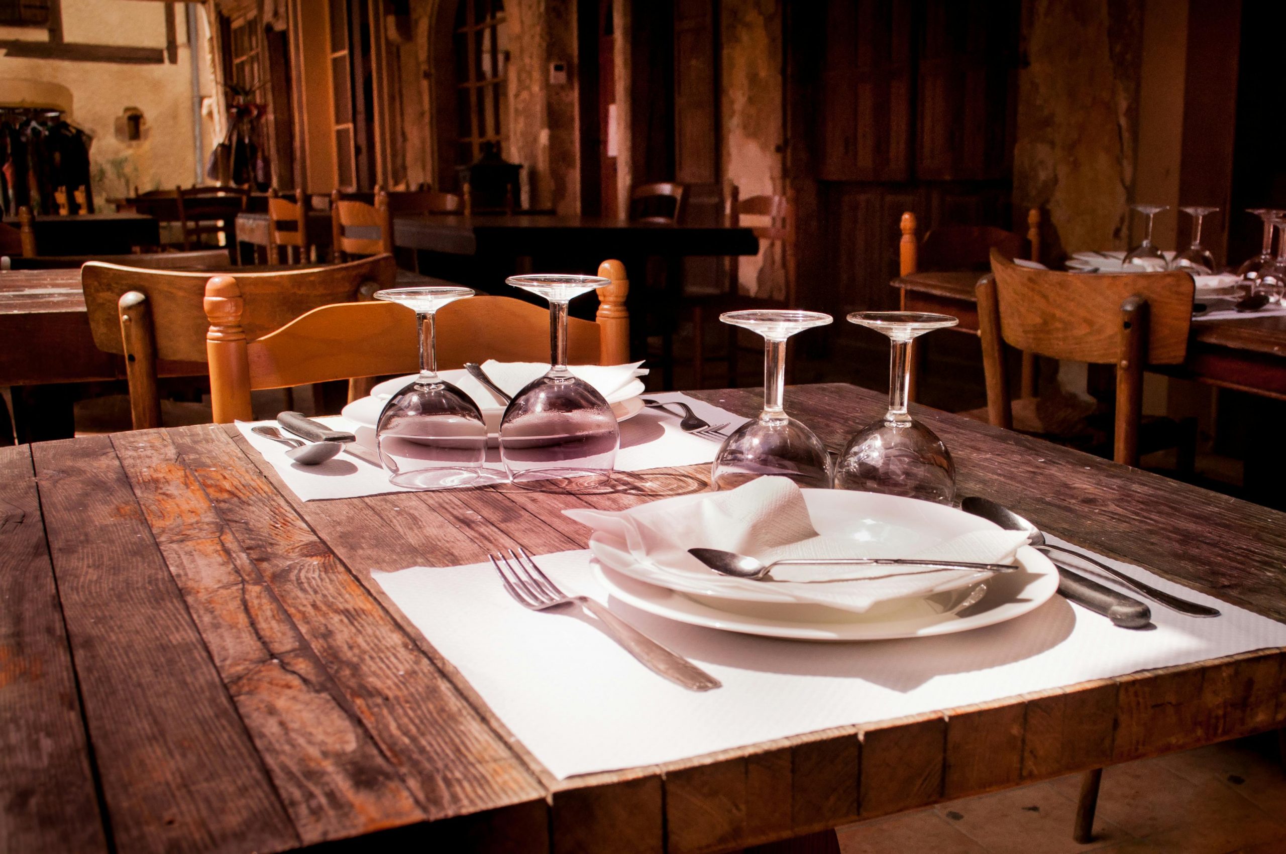 Home A rustic restaurant table set with wine glasses and cutlery invites guests to dine.
